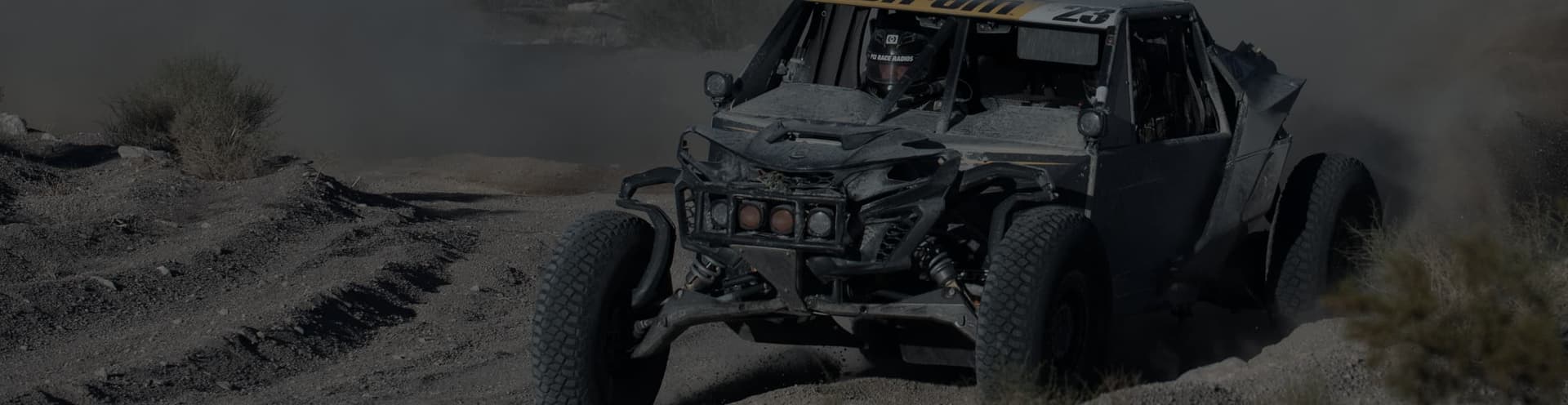 Багги Can-Am идёт по грунтовой трассе в облаке пыли